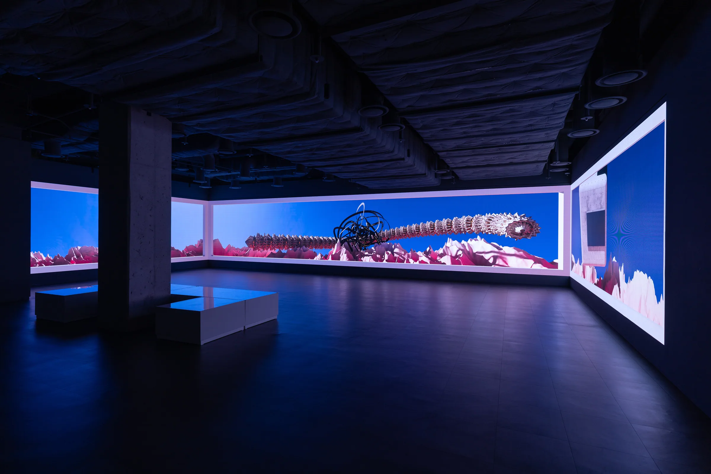 Minhyeok Seo, Post-Vanishing (2026) — three-plane media wall. 'Kkumteuli,' a colossal cylinder of bone, copper, gold, iron, and concrete, moves across a pink landscape.
