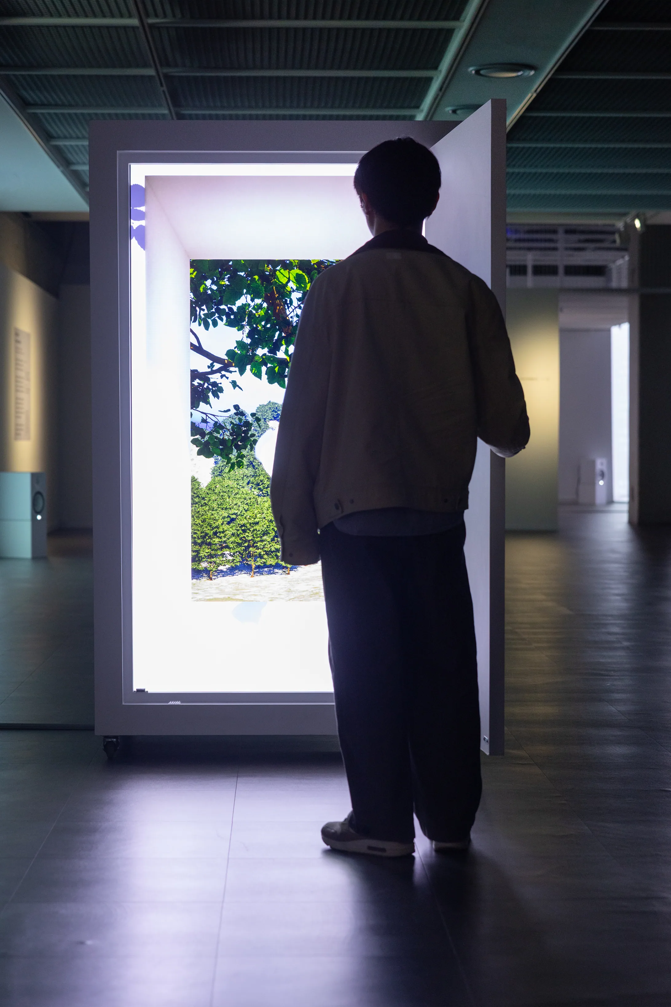 Minhyeok Seo, City'scape + Tied (2026) — a visitor stands at the small door, looking through a TV screen onto the landscape beyond. Single-channel video, 1'30.