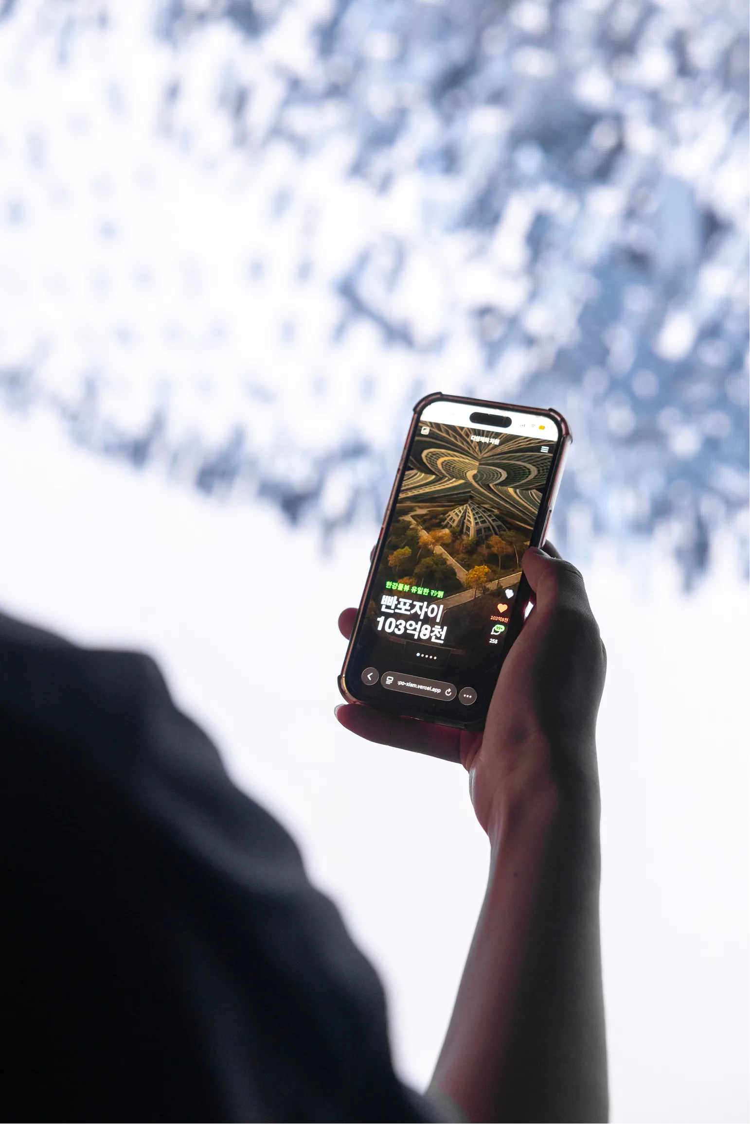 Jeanyoon Choi, ∫ (Banpo-Xism) (2026) — the multi-device web artwork running in a visitor's own phone. AI-generated apartment listings scroll on the device.